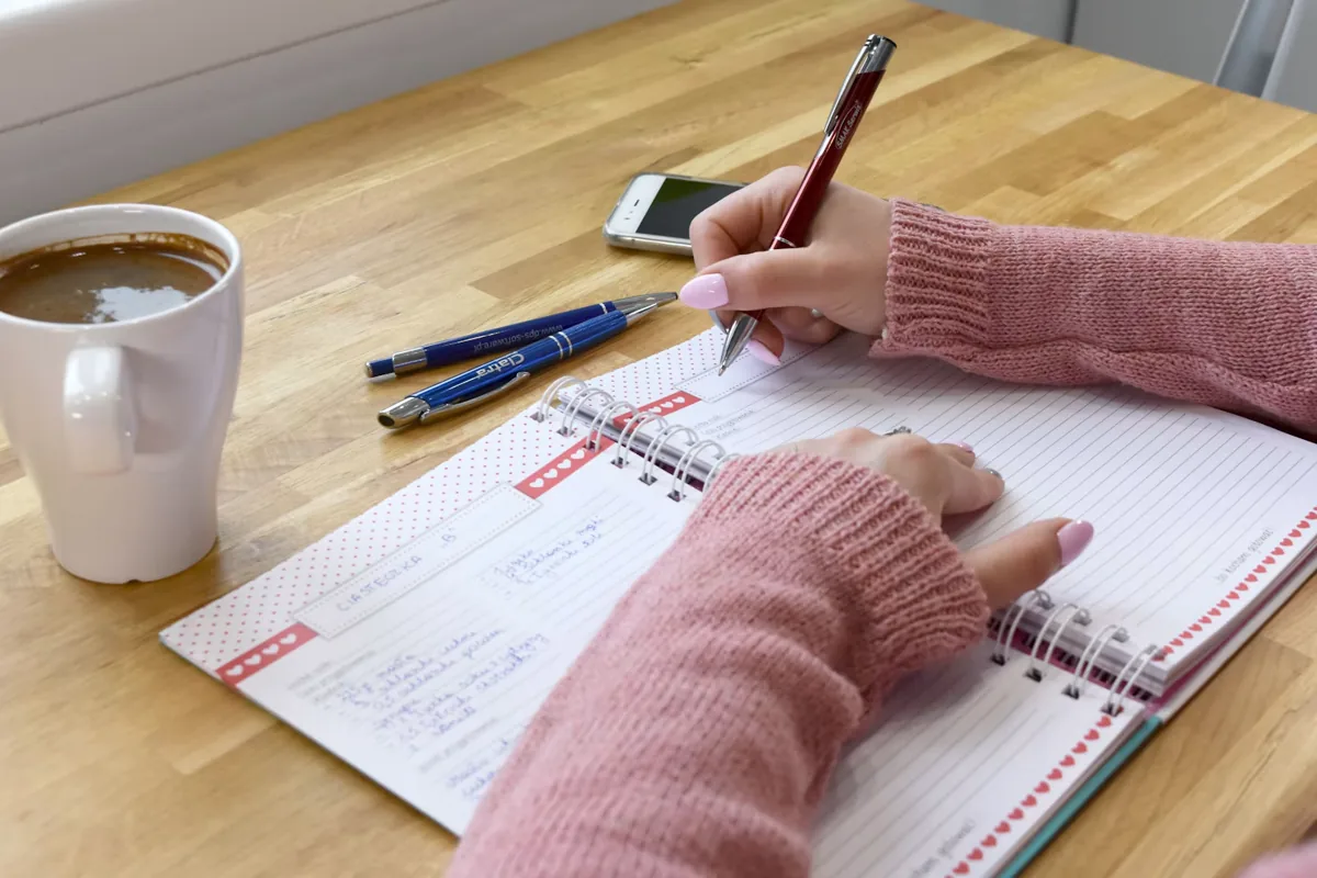開いた手帳に予定を書き込む手元